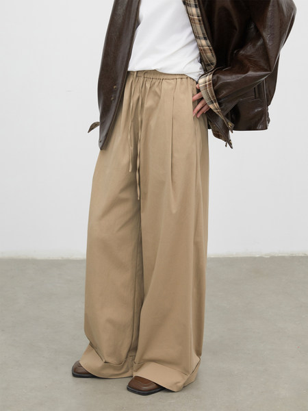 Model wearing wide-leg beige trousers with a brown leather jacket over a white top