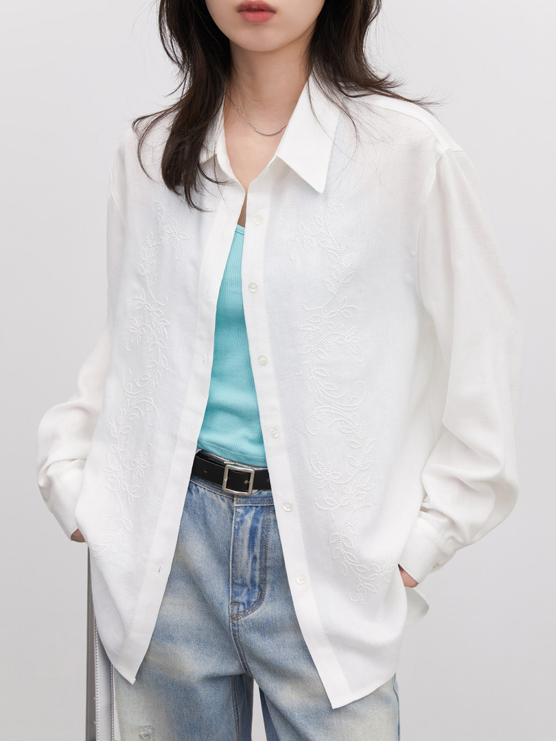 Model wearing a white embroidered button-up shirt with jeans