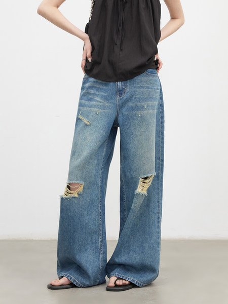 Model wearing distressed wide-leg blue jeans with a black top