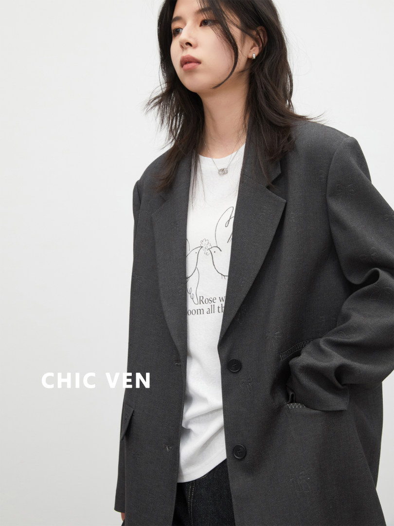 Model wearing a dark blazer over a graphic white T-shirt