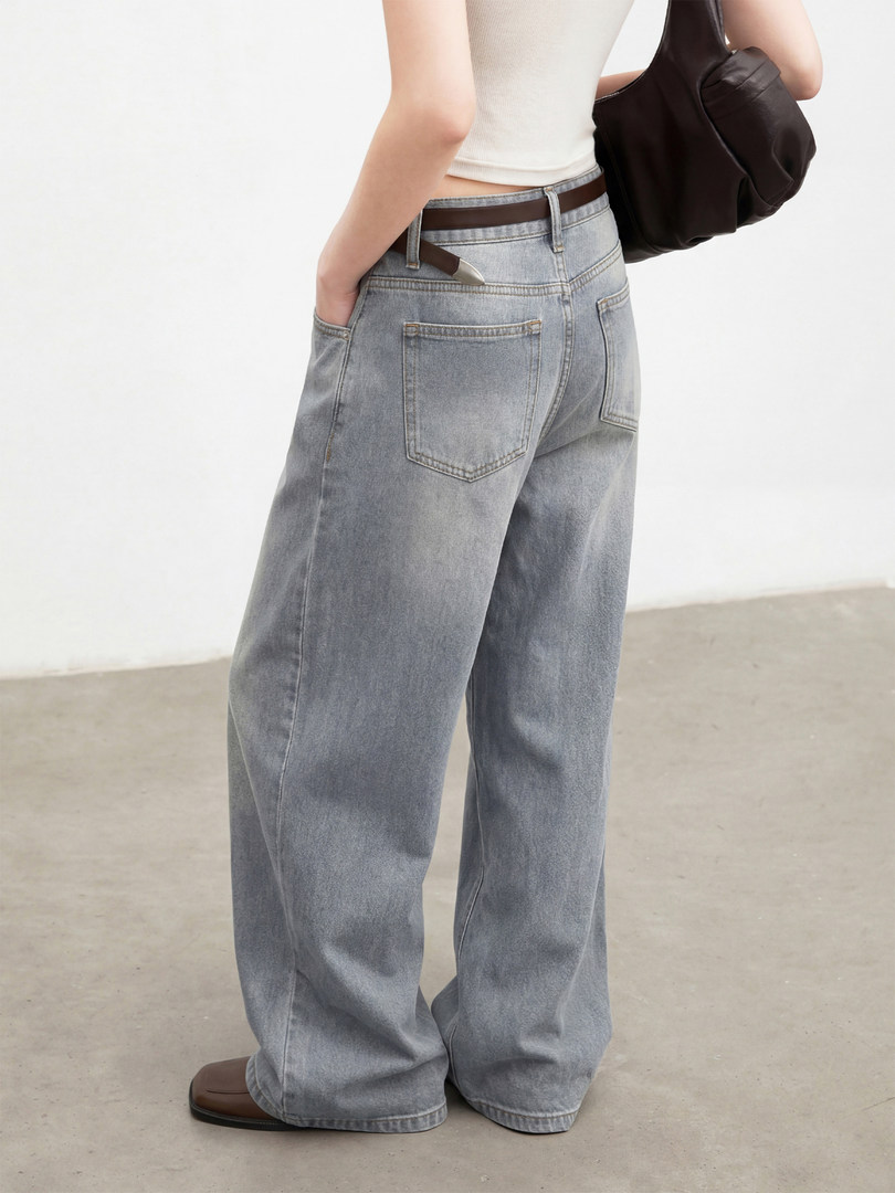 Model wearing light wash wide-leg jeans with a white top and brown bag