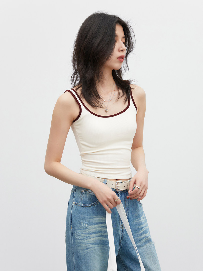 Model wearing a cream ribbed tank top with burgundy trim and blue jeans