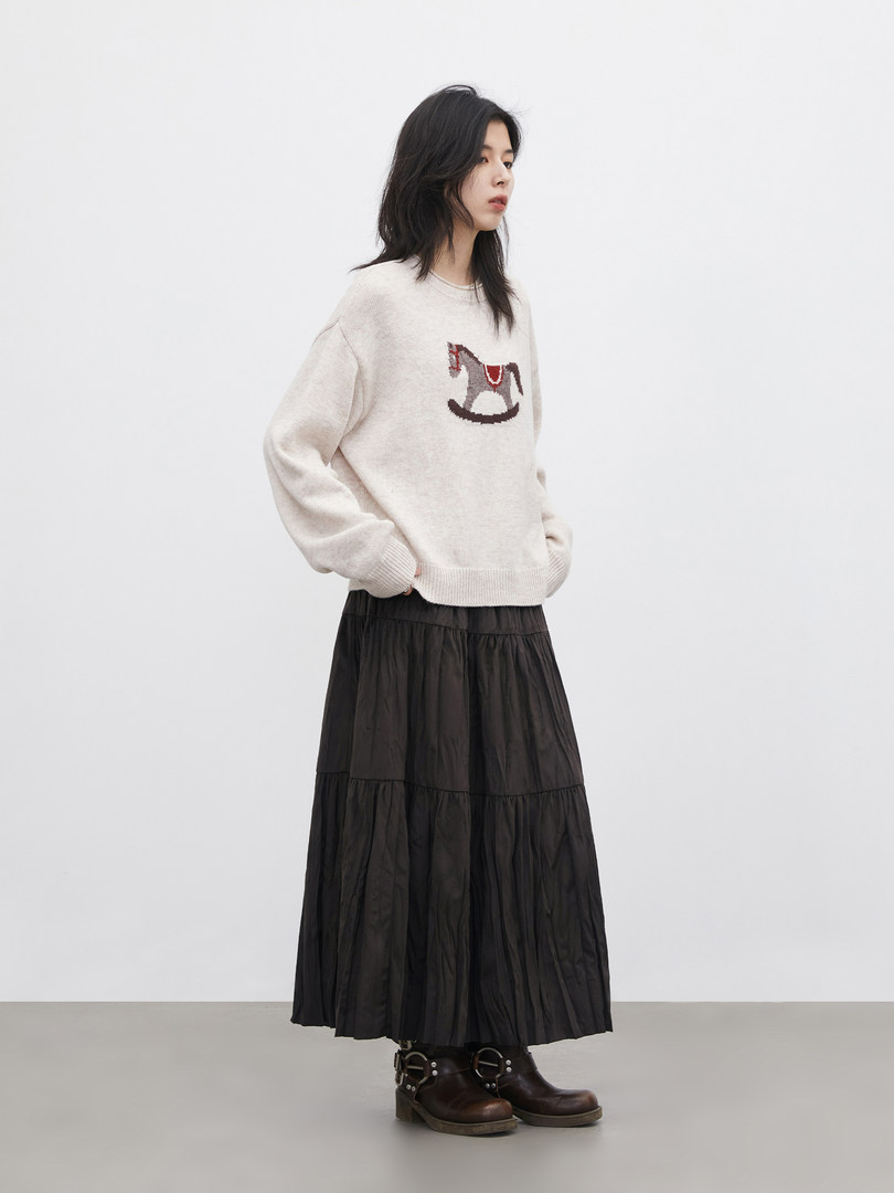 Model wearing a cream sweater with a horse graphic, black tiered skirt, and boots