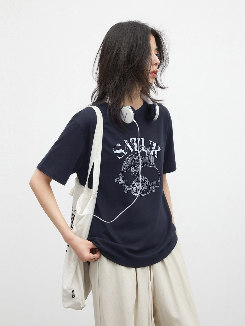 Model wearing a black graphic T-shirt with beige pants and a canvas tote bag