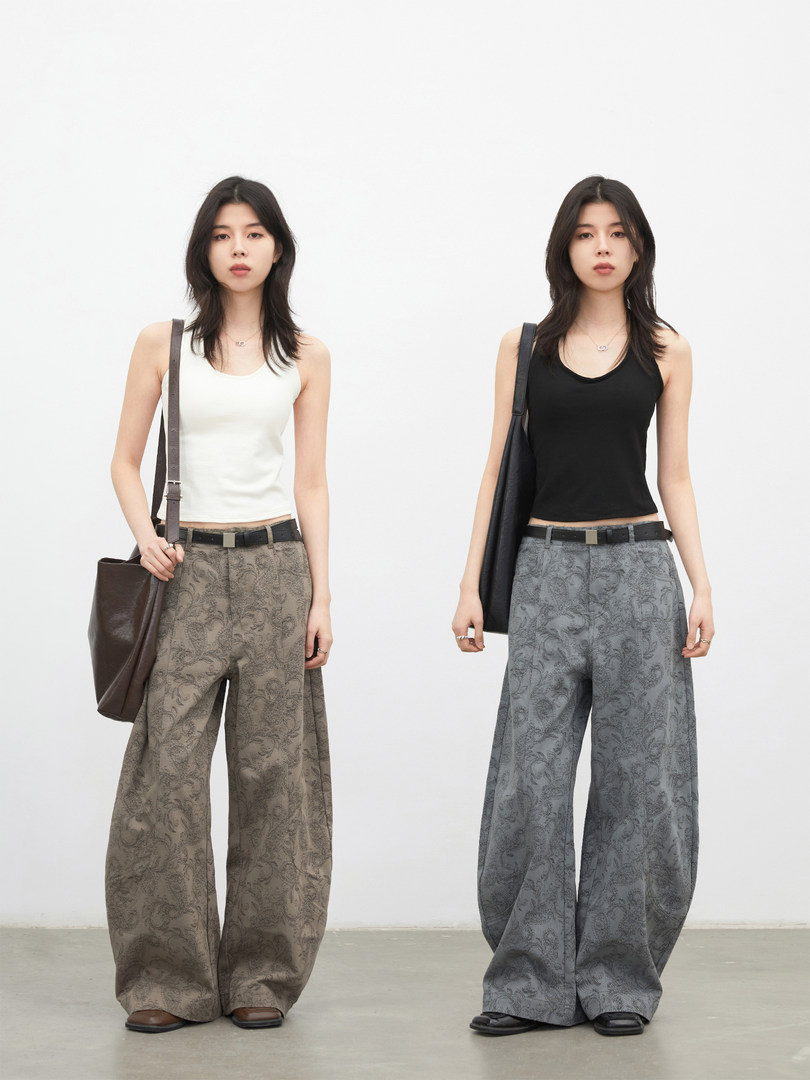 Two models wearing patterned wide-leg pants in brown and gray colorways