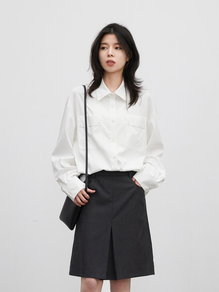 Woman wearing a white button-up shirt with a dark skirt and small black shoulder bag