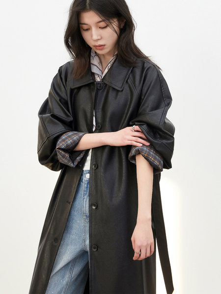 Model wearing a black leather long coat over jeans