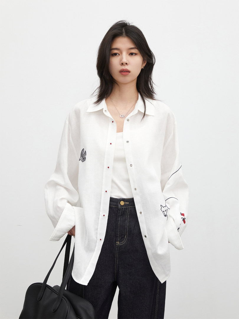 Model wearing a white sheer button-up shirt with dark jeans