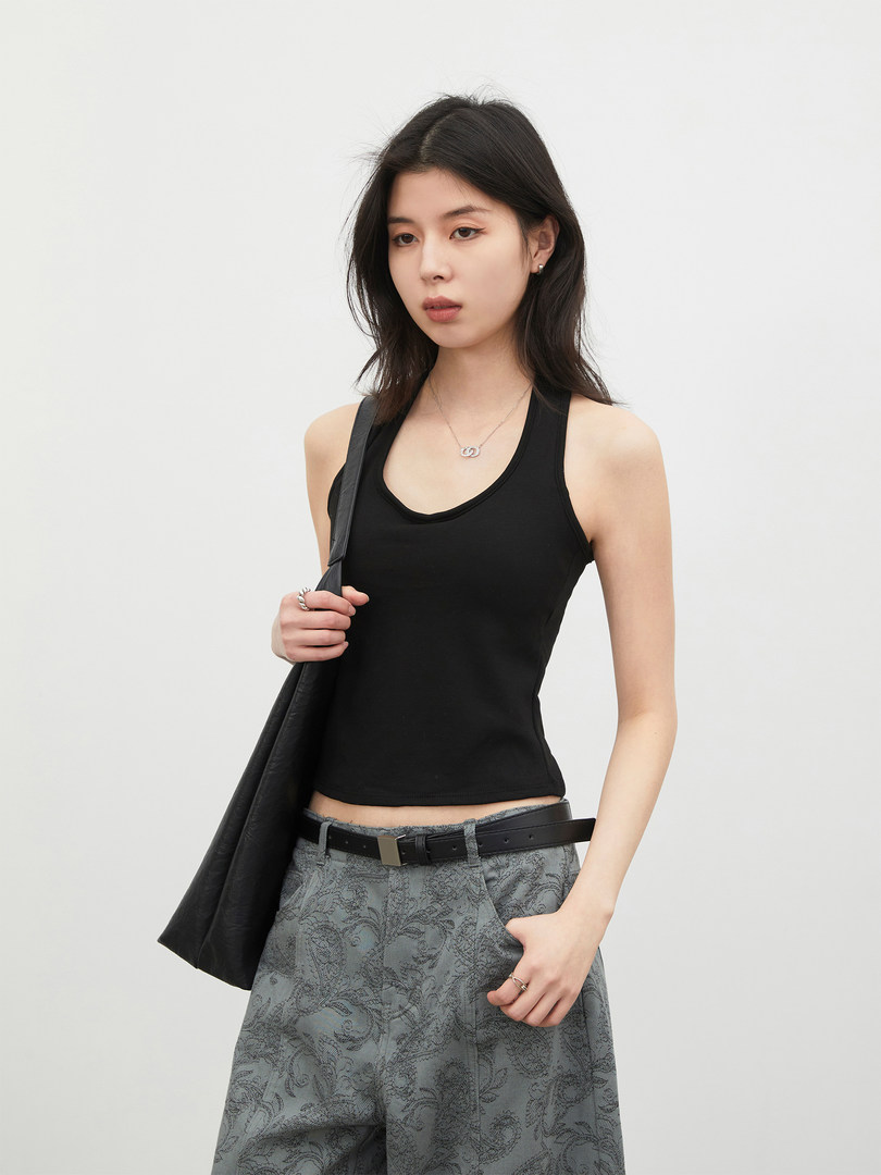 Model wearing a black tank top with patterned gray pants and a black jacket
