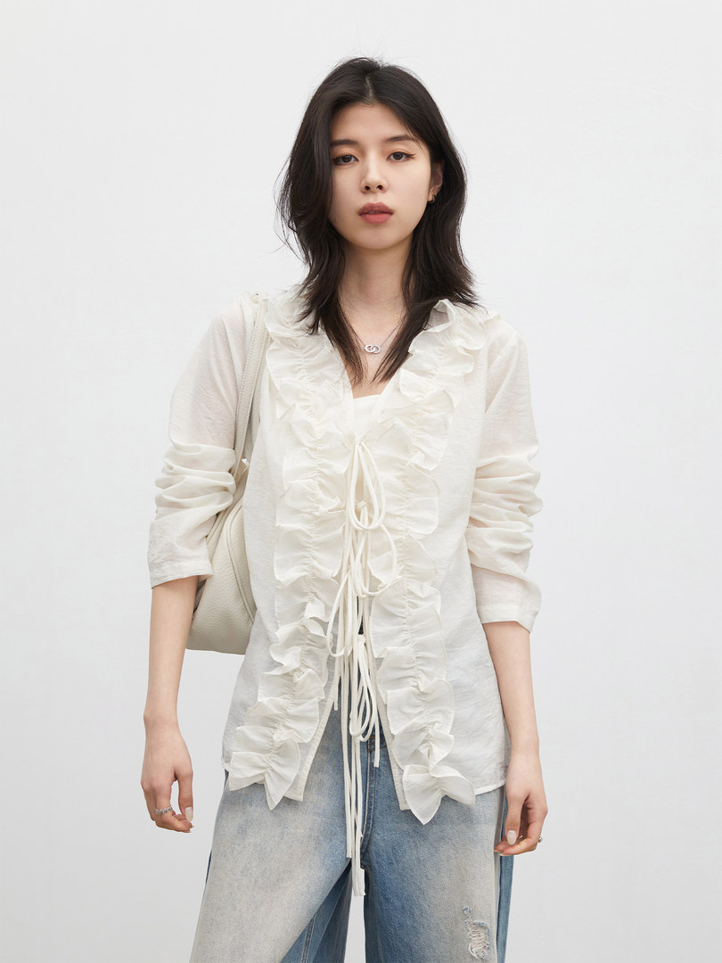 Model wearing a white ruffled blouse with light blue jeans