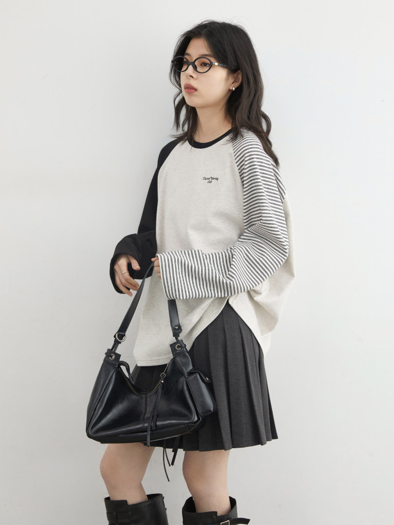 Model wearing a black-and-white striped long-sleeve top with a black skirt and handbag