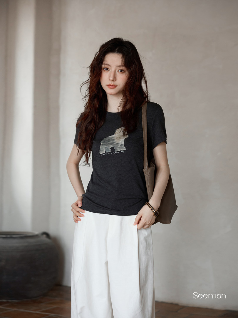 Woman wearing a dark graphic T-shirt with white wide-leg pants and a shoulder bag