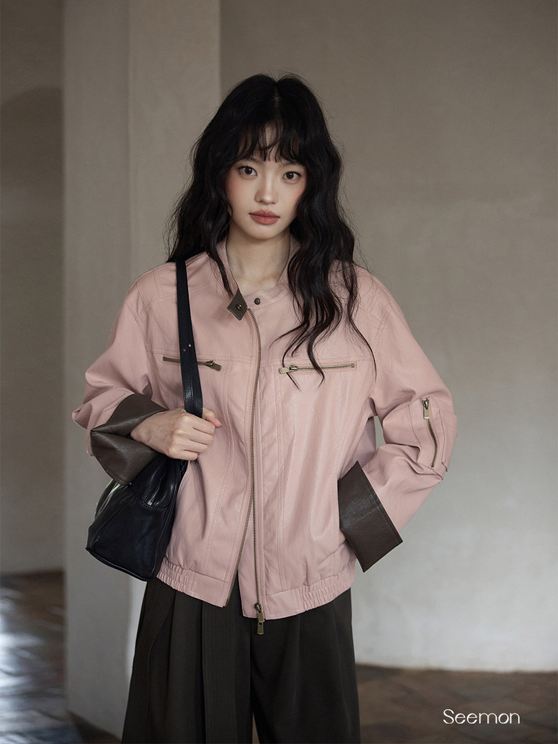 Model wearing a pink zip-up jacket with black shoulder bag