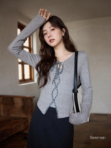 Model wearing a gray long-sleeve knit top with tie-front detail