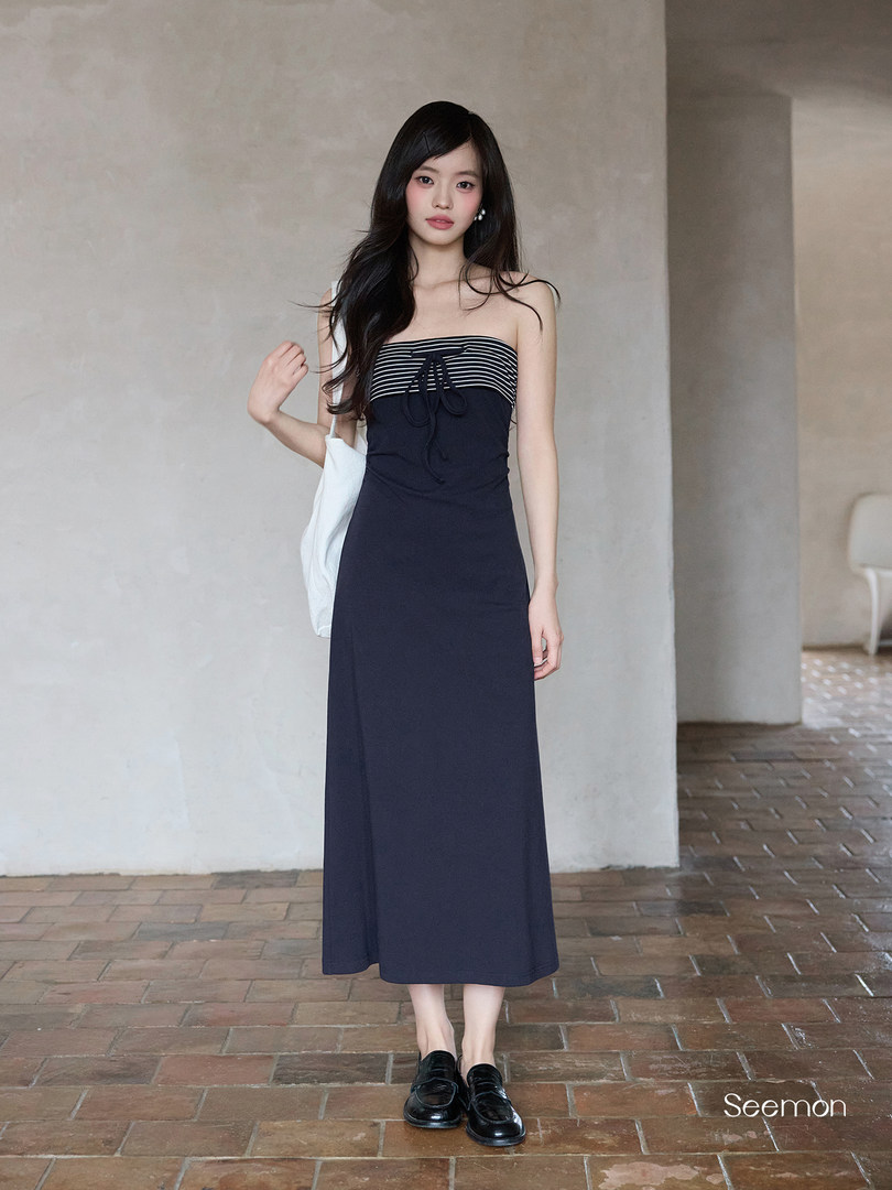 Model wearing a navy strapless midi dress with striped bodice and black loafers