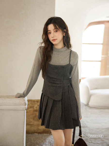 Model wearing a gray long-sleeve layered pleated dress outfit