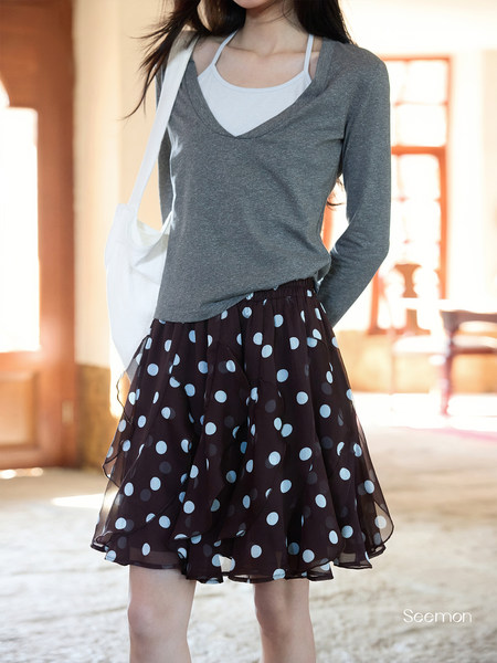 Model wearing a gray long-sleeve top and black polka dot skirt