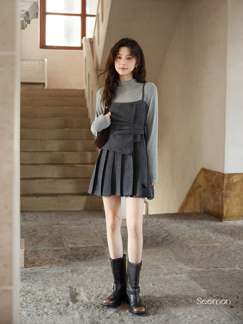 Model wearing a gray layered dress with long sleeves and black boots