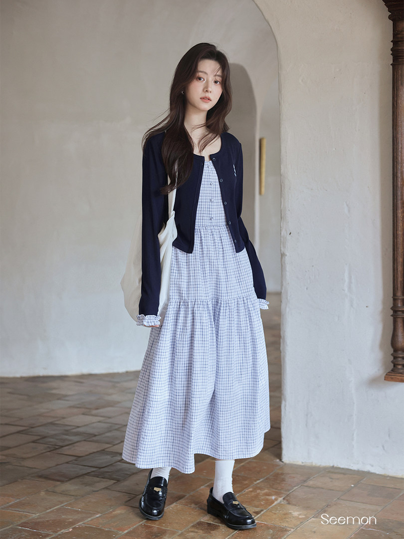 Model wearing a navy cardigan over a light checkered midi dress