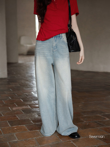 Model wearing light-wash wide-leg embellished jeans with a red top and black bag