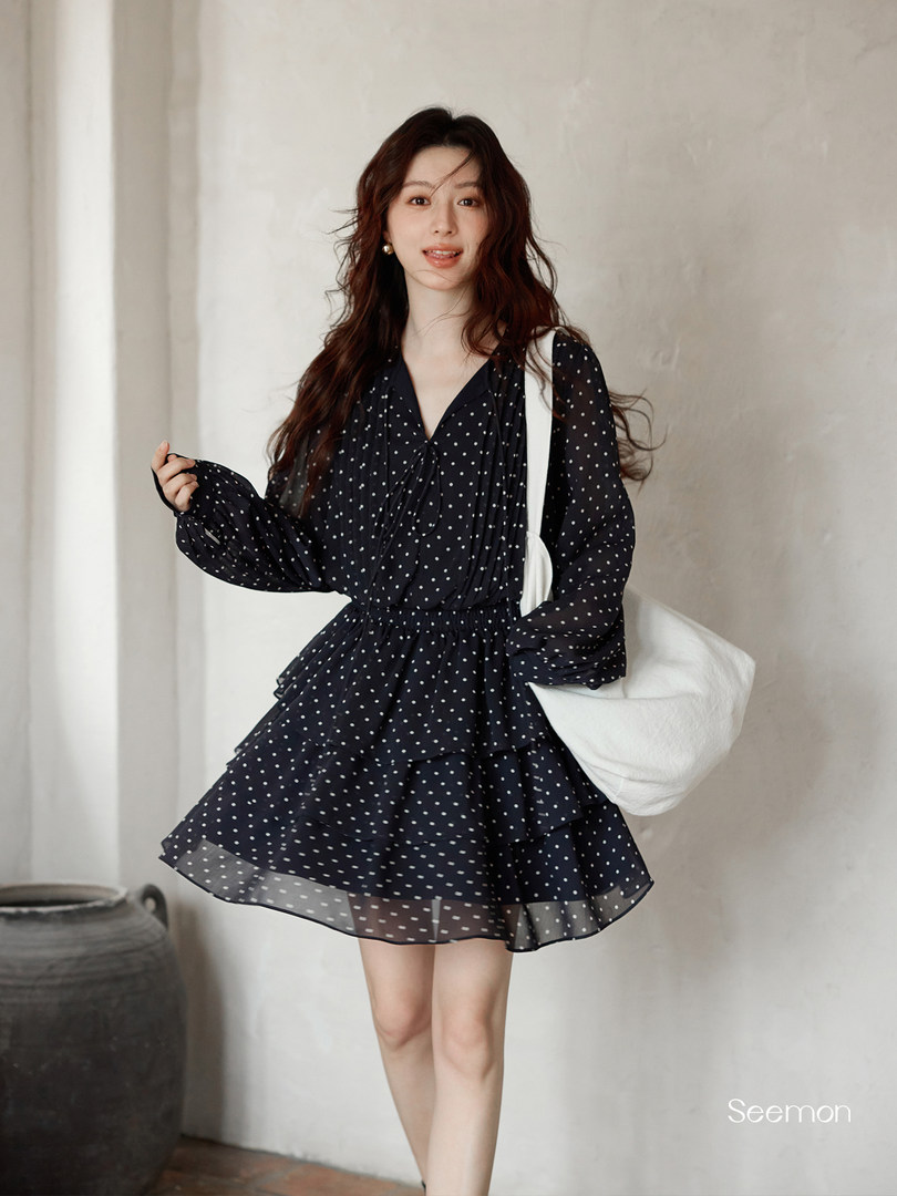 Model wearing a black polka dot long-sleeve mini dress with a layered skirt