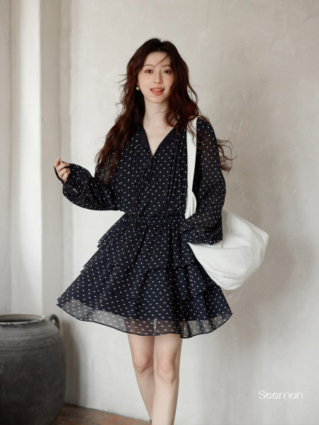 Model wearing a black polka dot long-sleeve mini dress with a layered skirt