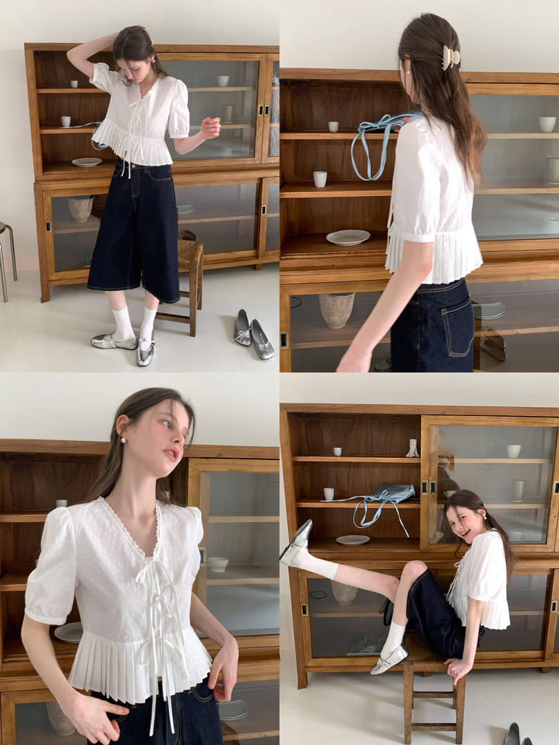 White short-sleeve pleated blouse worn on a model with dark wide-leg jeans