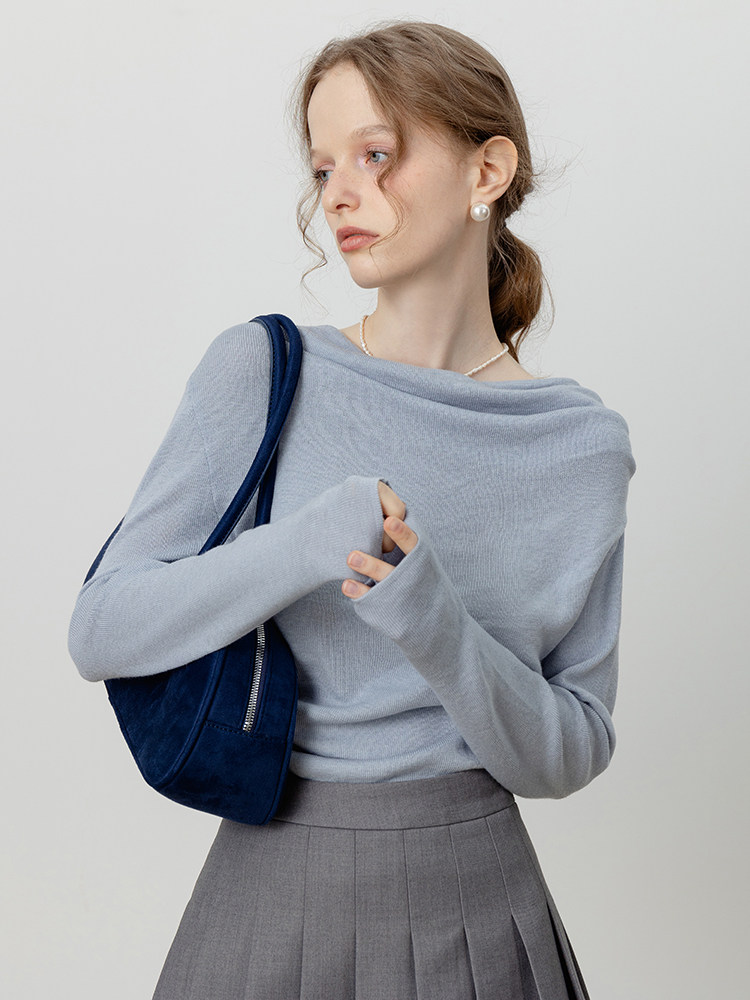 Model wearing a light blue off-shoulder knit top with a navy shoulder bag and gray skirt