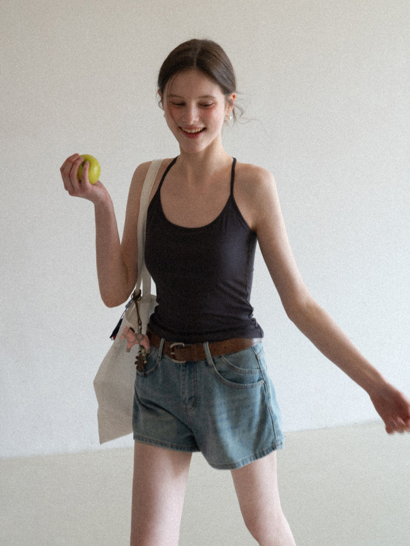 Woman wearing a black tank top with denim shorts and a tote bag