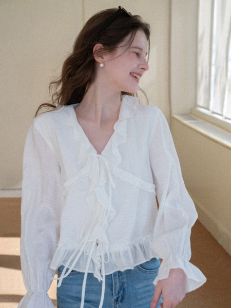 Woman wearing a white sheer ruffled blouse with long sleeves