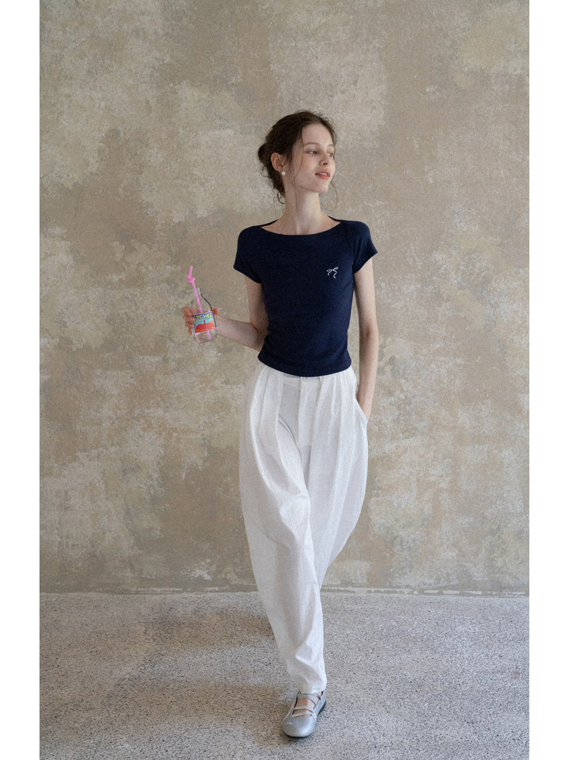Model wearing a navy short-sleeve top with white pants and flats