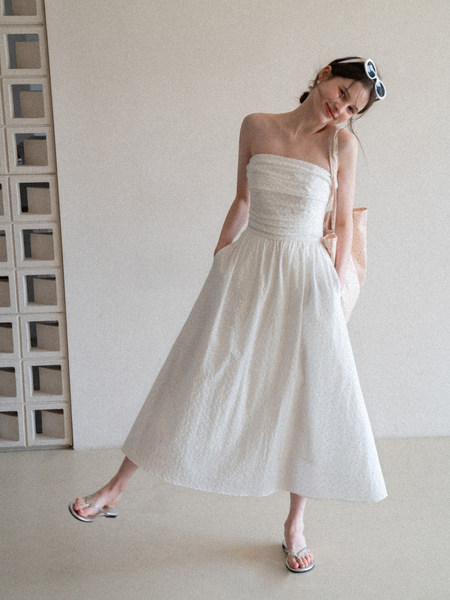 Woman wearing a white strapless midi dress with a full skirt