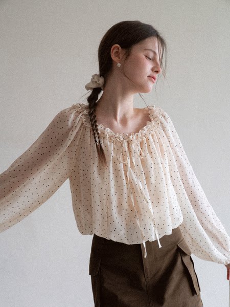 Woman wearing a sheer polka dot ruffled blouse