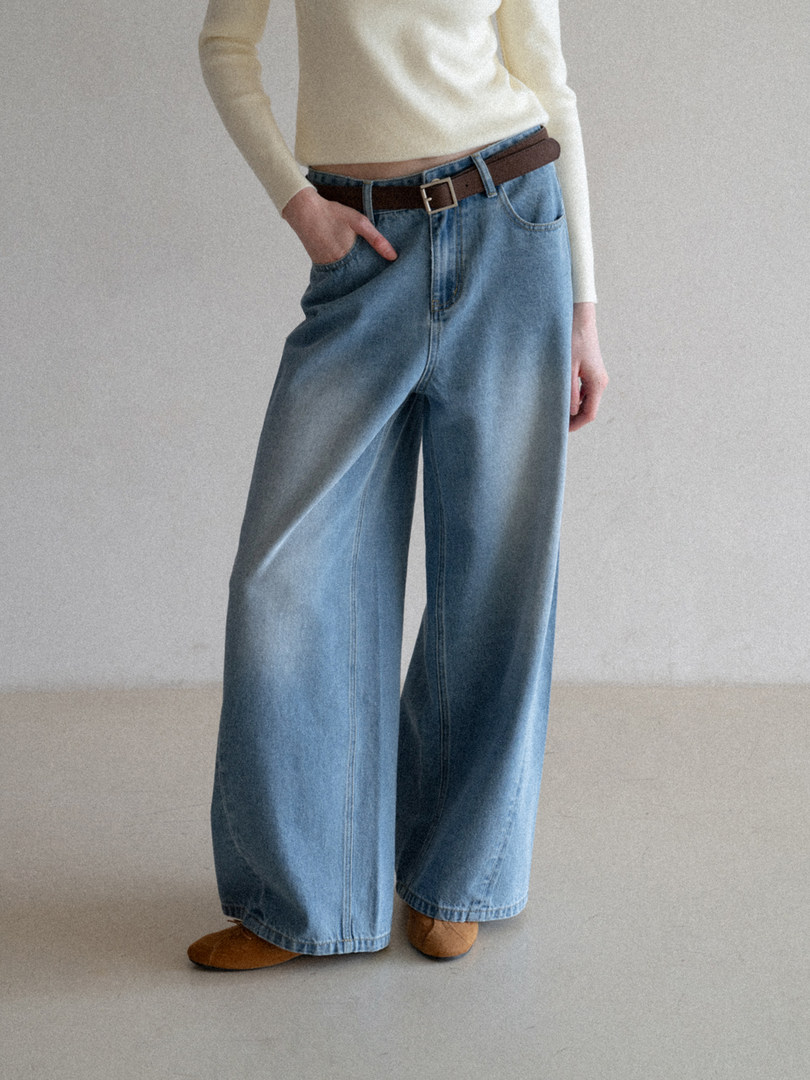 Wide-leg blue denim jeans worn with a belt on a model