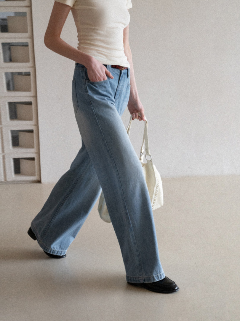 Model wearing light blue wide-leg jeans with a white top and black shoes