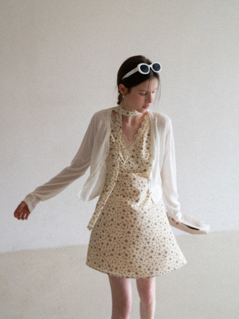 Woman wearing a cream floral dress with a sheer white cardigan and sunglasses