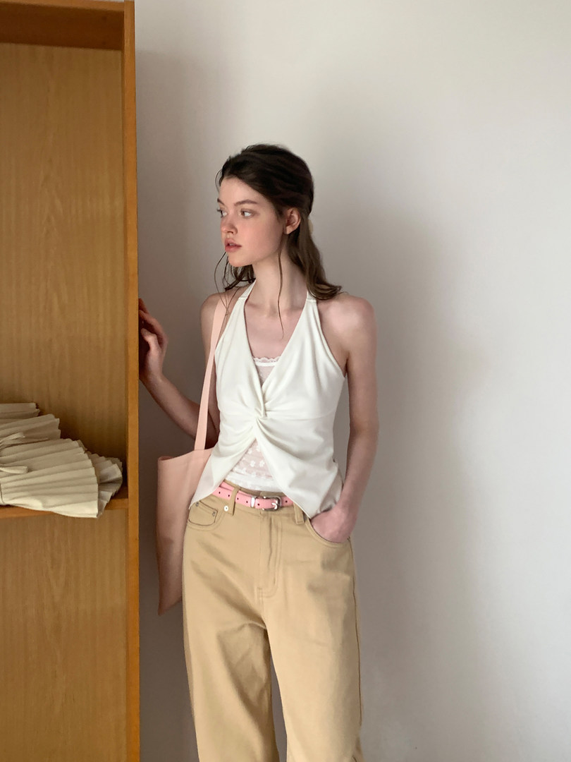 Model wearing a white halter top with beige trousers