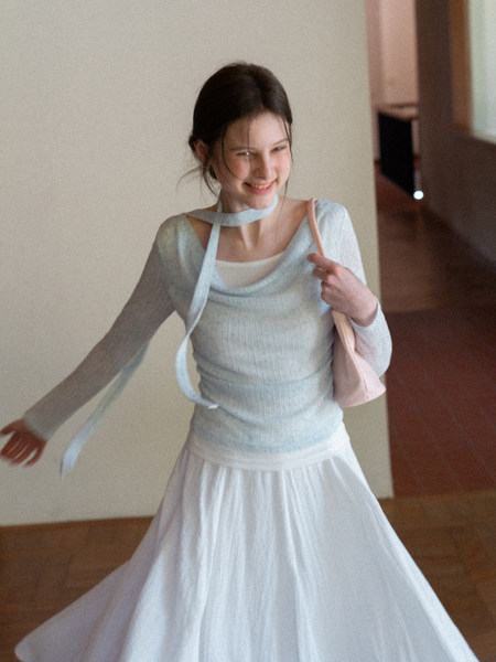 Model wearing a light blue sheer long-sleeve top with a white flowing skirt
