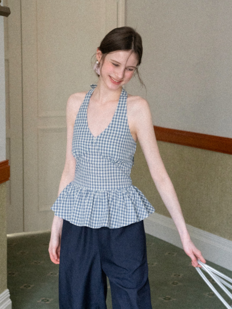 Model wearing a blue gingham halter peplum top