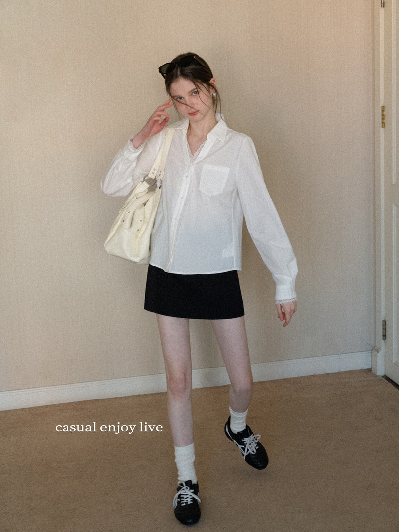 Model wearing a white button-up shirt with a black mini skirt, handbag, and sneakers