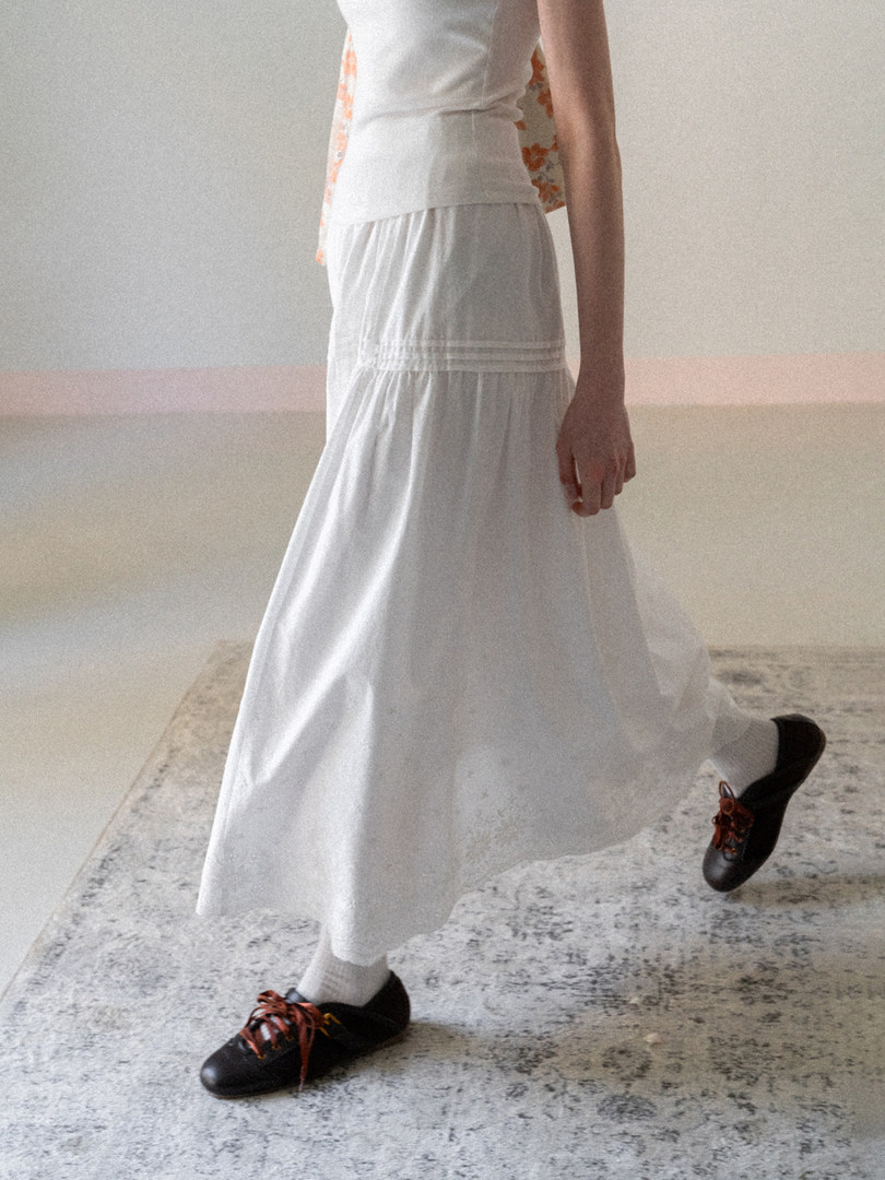 Model wearing a white flowy skirt with black lace-up shoes