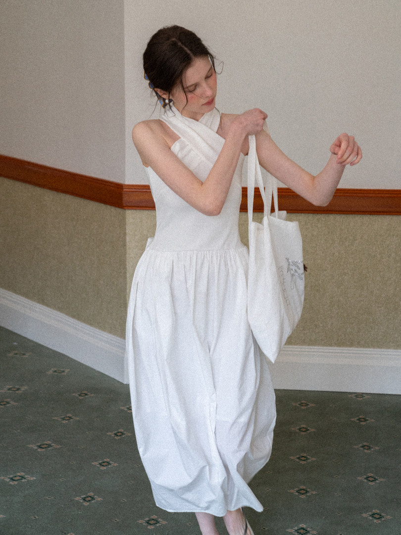 Woman wearing a white sleeveless midi dress with a halter neckline