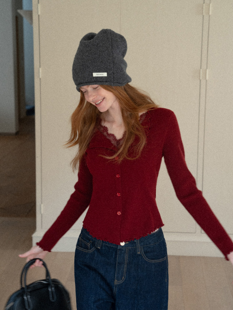 Model wearing a red button-front cardigan, dark jeans, and a gray knit beanie