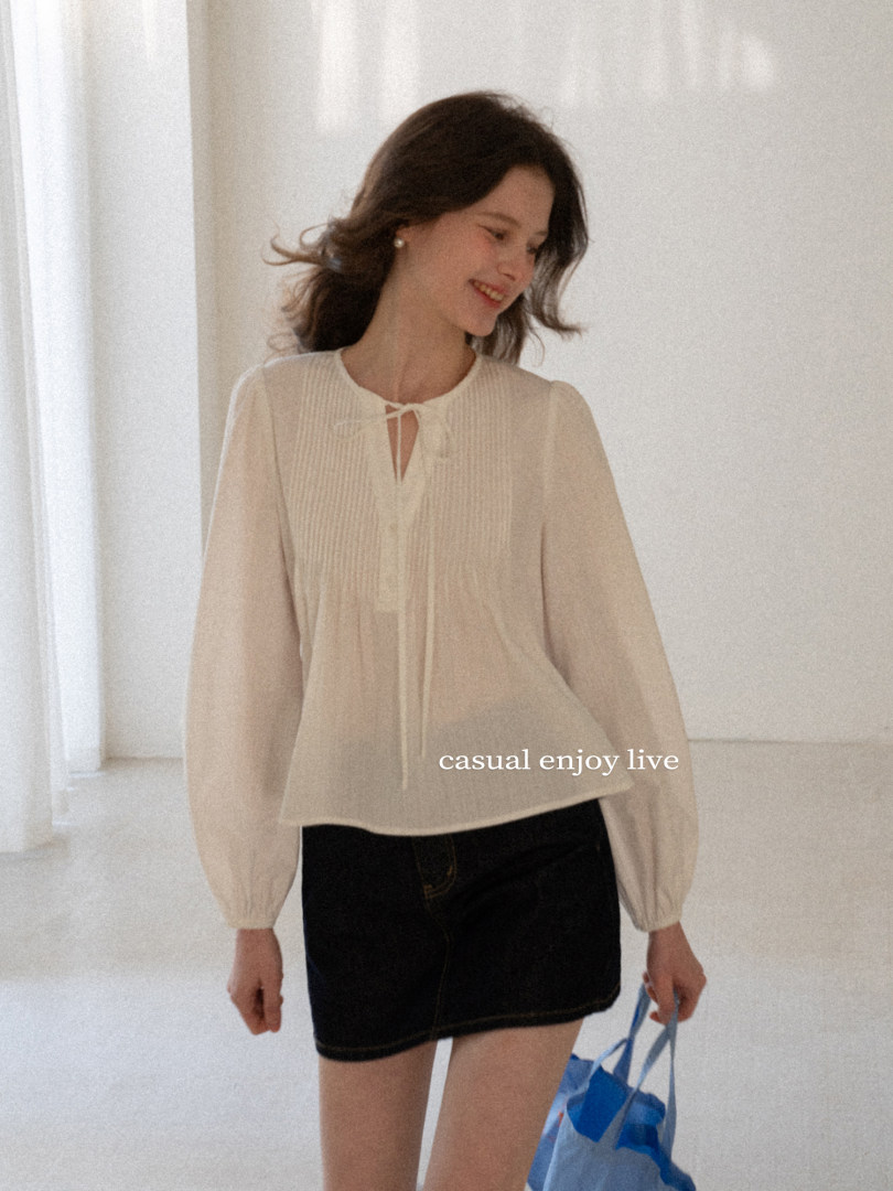 Woman wearing a white sheer long-sleeve blouse and black mini skirt