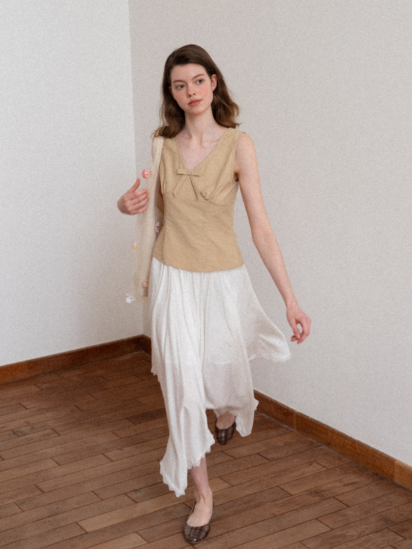 Model wearing a beige sleeveless top with a white flowy skirt