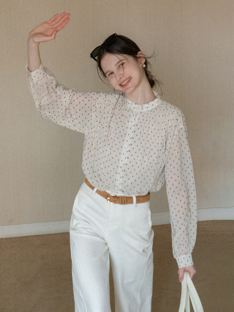 Woman wearing a white polka dot blouse with white trousers