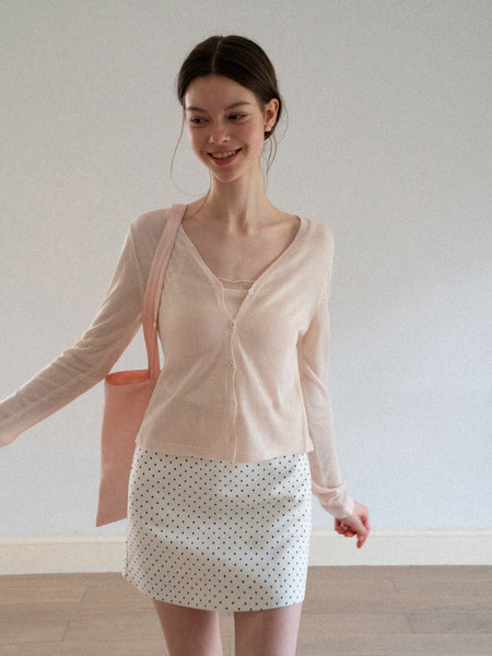 Model wearing a pale pink cardigan with a white polka dot skirt