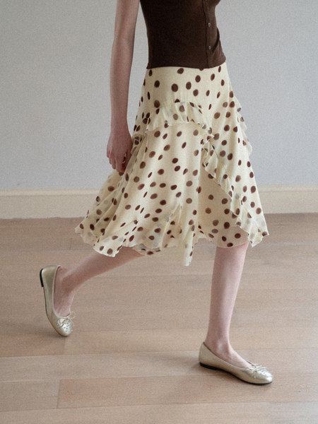 Model wearing a cream polka dot ruffled skirt with beige flats