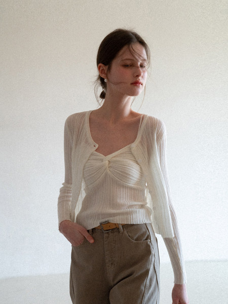 Model wearing a cream ribbed knit cardigan and top with brown trousers