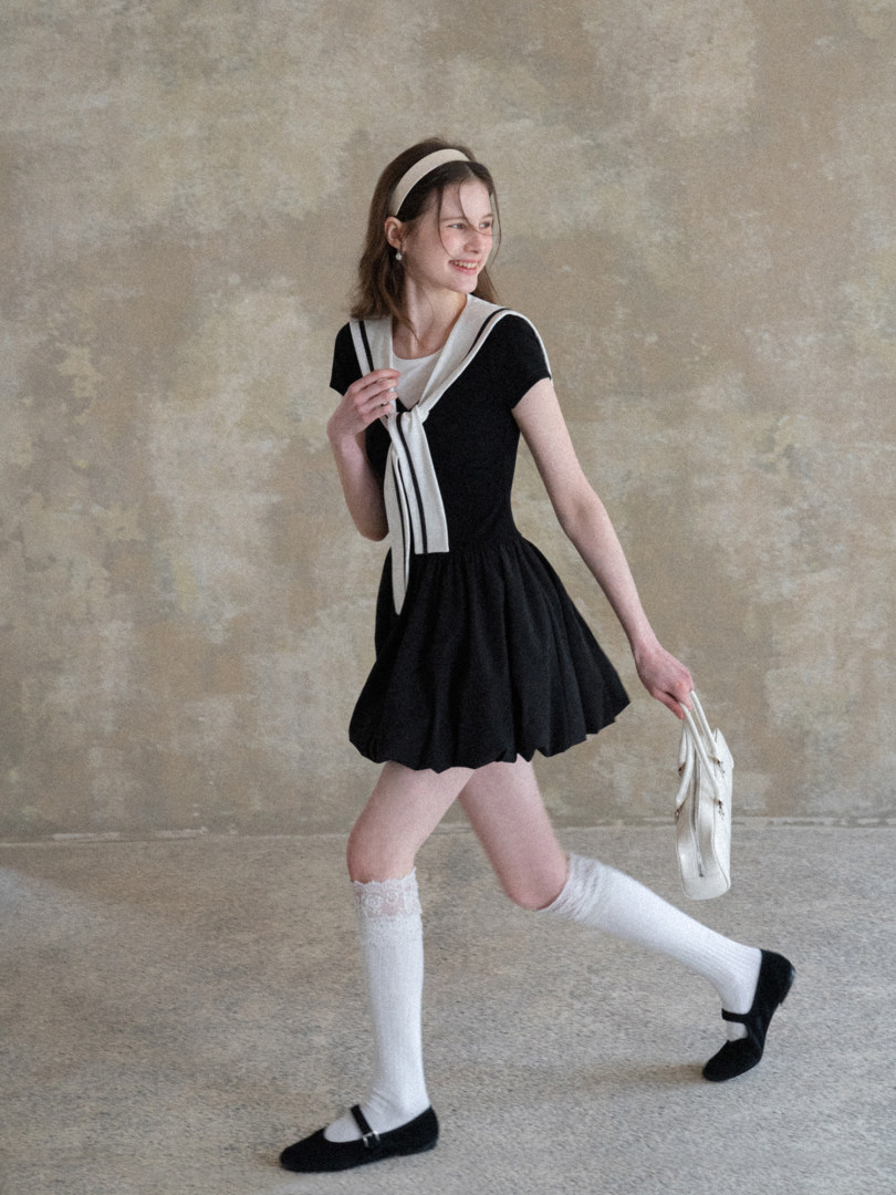 Model wearing a black-and-white sailor-style dress with knee-high socks and Mary Jane shoes